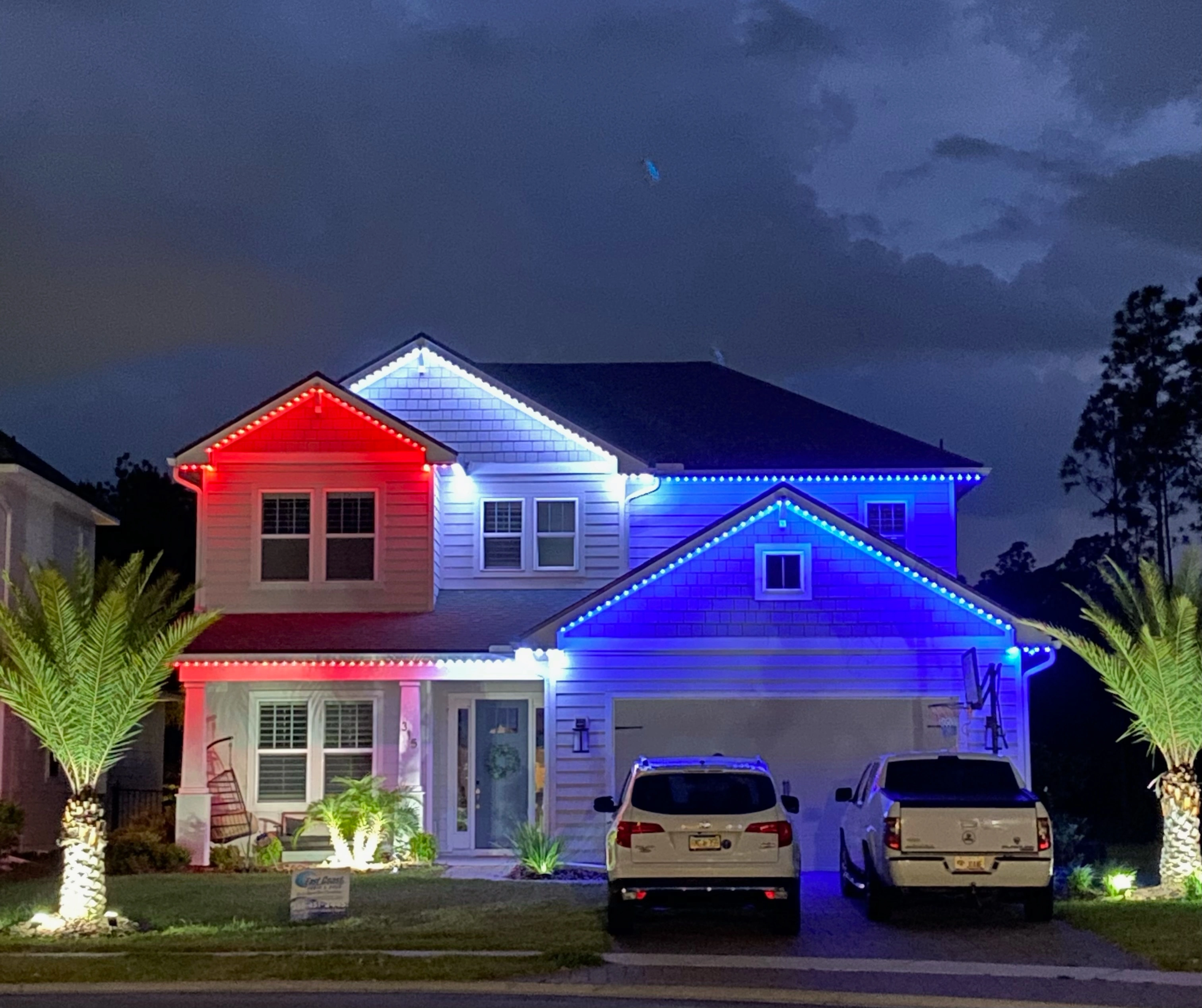 Two-story Jacksonville-area home lit red, white and blue with palm trees out front